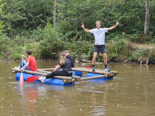 Vier mensen op een zelfgebouwd vlot op het water