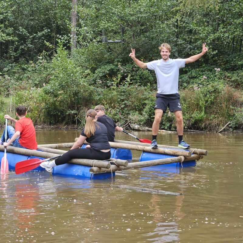 Vier mensen op een zelfgebouwd vlot op het water