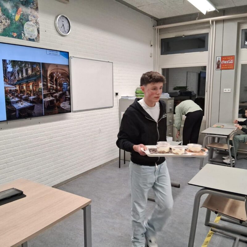 Jongen met dienblad loopt door een lokaal