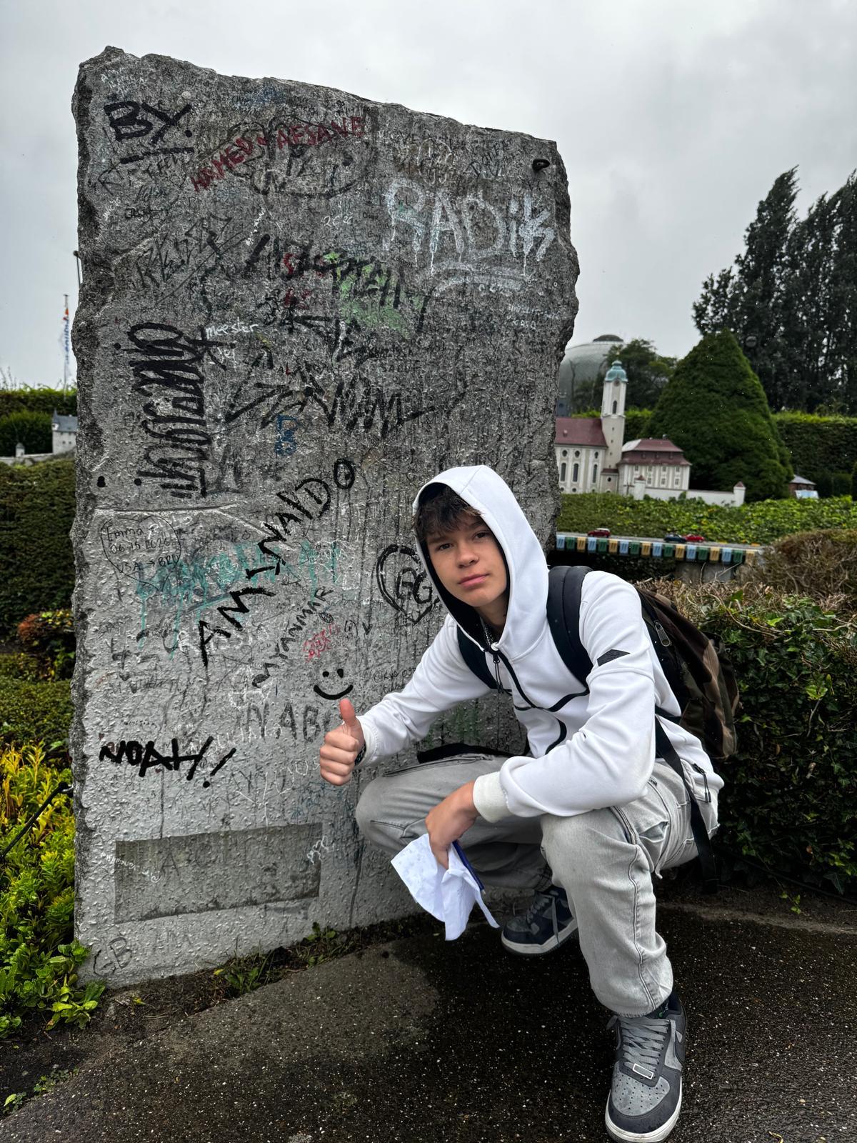 Jongen poseert voor een betonnen muur met graffiti