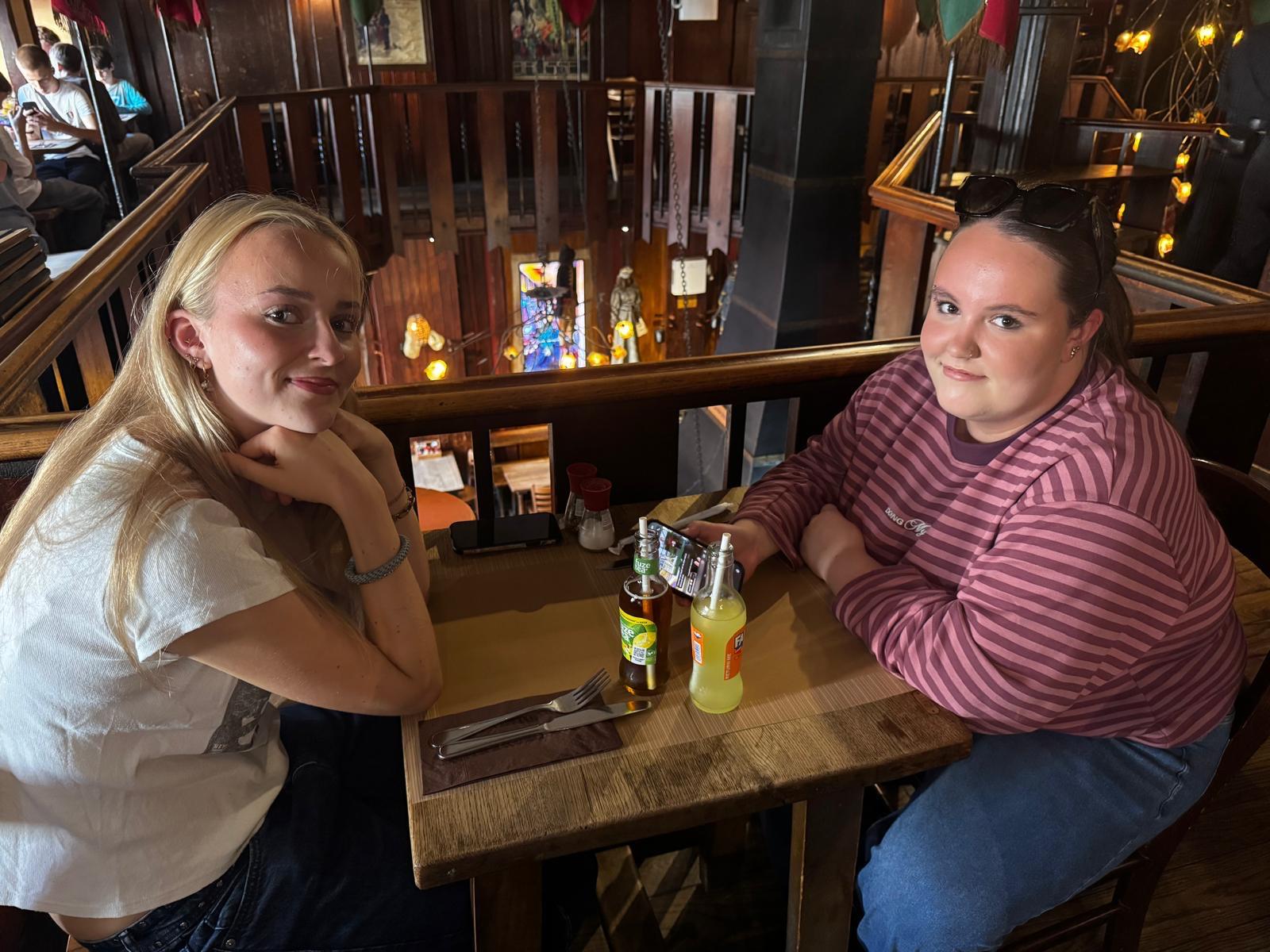 Twee vrouwen zitten tegenover elkaar in een donkerbruin café