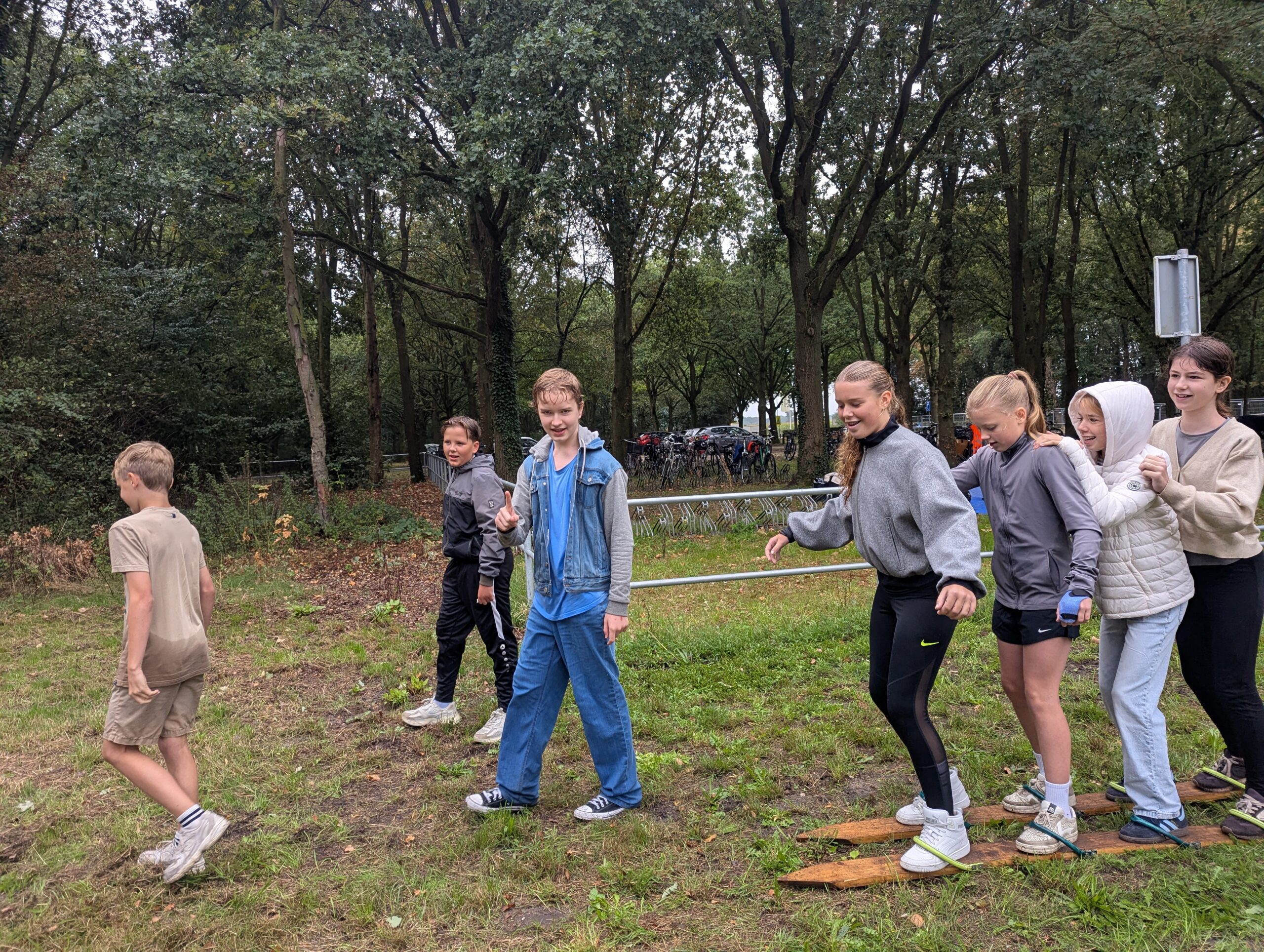 Kinderen houden elkaar vast op houten ski's.
